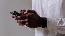 person in white dress shirt holding black smartphone