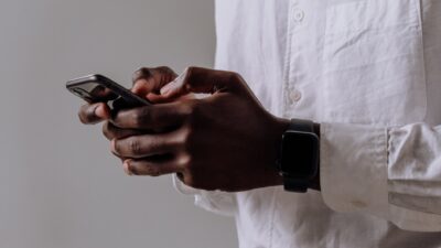 person in white dress shirt holding black smartphone